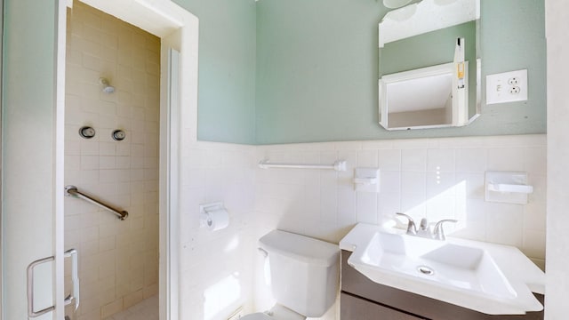 bathroom with toilet, vanity, and tile walls