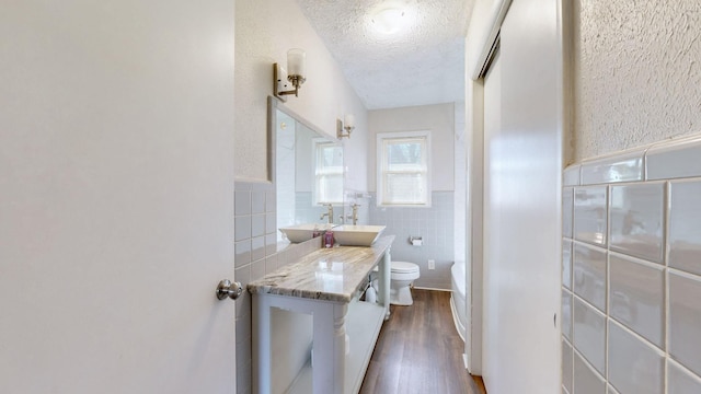 bathroom with toilet, a textured ceiling, hardwood / wood-style flooring, tile walls, and vanity