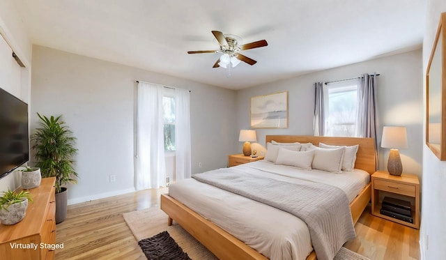 bedroom featuring ceiling fan, light hardwood / wood-style floors, and multiple windows