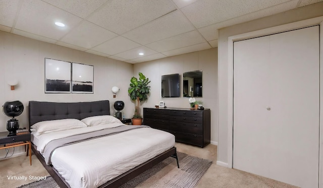 carpeted bedroom with a drop ceiling and a closet