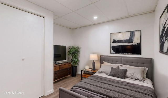 bedroom featuring a paneled ceiling and light wood-type flooring