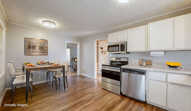 kitchen featuring white cabinets, light hardwood / wood-style flooring, appliances with stainless steel finishes, and a textured ceiling