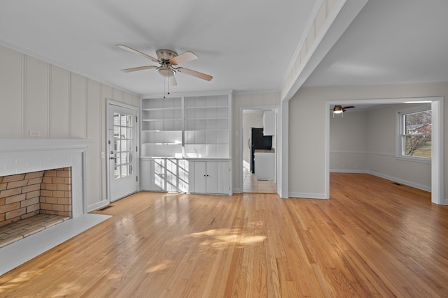 unfurnished living room featuring a fireplace, a wealth of natural light, ceiling fan, and crown molding