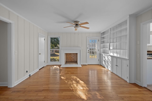 unfurnished living room with built in shelves, ceiling fan, plenty of natural light, and ornamental molding