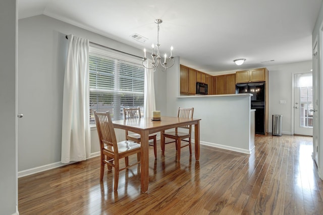 dining room featuring dark wood-type flooring, a chandelier, and lofted ceiling