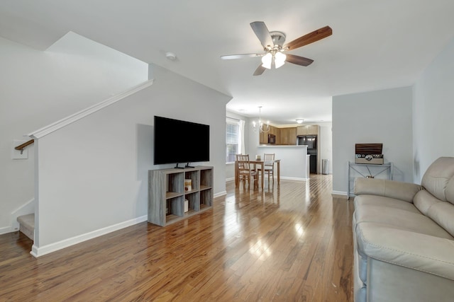 living room with ceiling fan with notable chandelier and light wood-type flooring