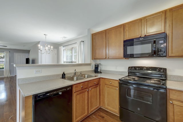 kitchen with dark wood-type flooring, an inviting chandelier, black appliances, sink, and kitchen peninsula