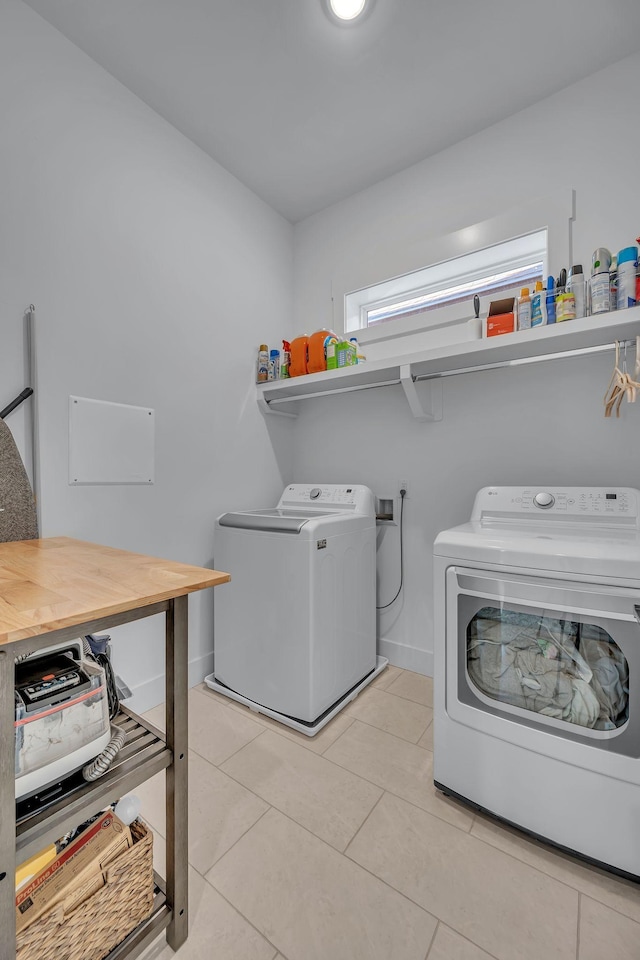 clothes washing area featuring washing machine and clothes dryer and light tile patterned floors