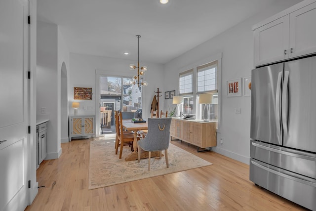 dining room with light wood-type flooring and an inviting chandelier