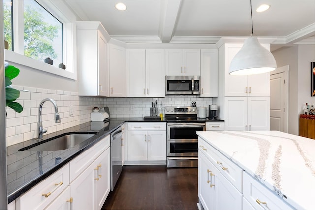 kitchen with dark stone counters, hanging light fixtures, sink, appliances with stainless steel finishes, and white cabinetry