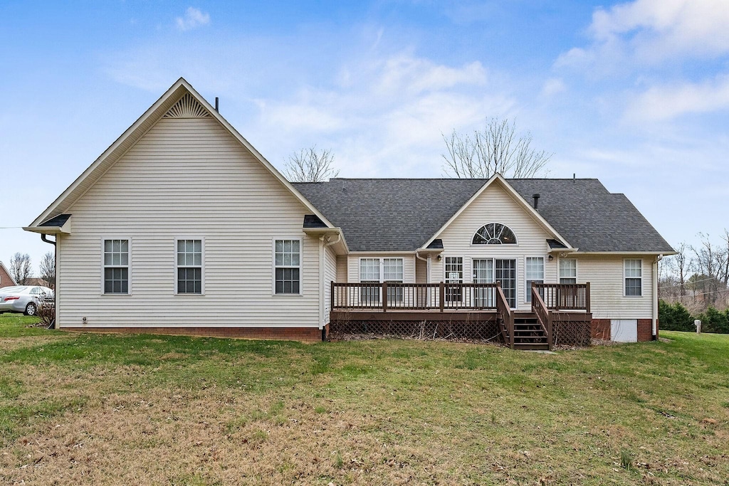 rear view of property featuring a lawn and a deck