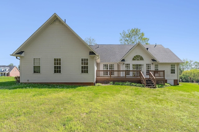 rear view of house featuring a lawn, a shingled roof, and a deck