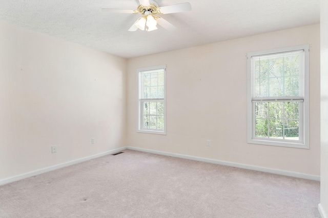 unfurnished room with ceiling fan, light carpet, visible vents, and baseboards