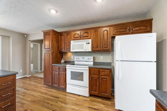 kitchen featuring recessed lighting, dark countertops, white appliances, light wood-style flooring, and a textured ceiling