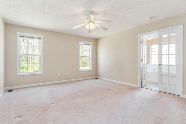 empty room featuring baseboards, a ceiling fan, and light carpet