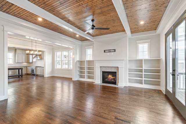 unfurnished living room featuring beamed ceiling, a healthy amount of sunlight, and wood ceiling