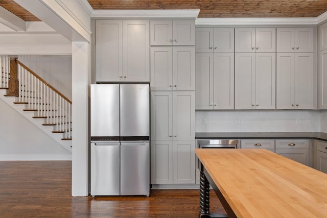 kitchen featuring wood counters, decorative backsplash, gray cabinets, dark hardwood / wood-style flooring, and stainless steel refrigerator