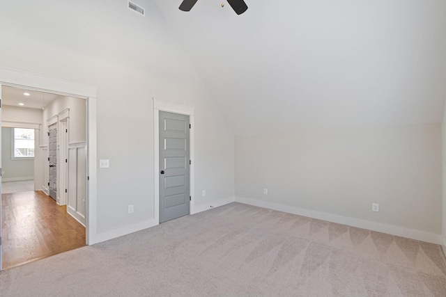 empty room with light colored carpet, vaulted ceiling, and ceiling fan