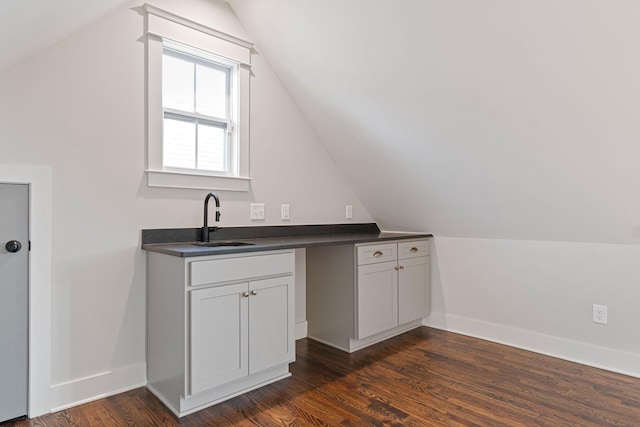 interior space with dark hardwood / wood-style floors, white cabinetry, lofted ceiling, and sink