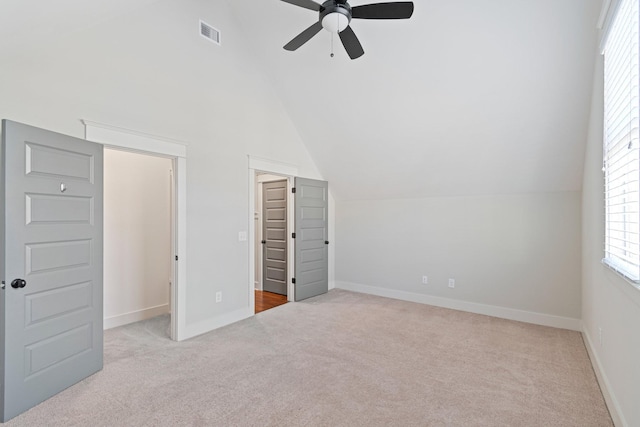 unfurnished bedroom with ceiling fan, a closet, light carpet, and vaulted ceiling