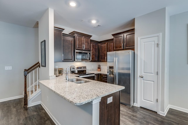 kitchen featuring kitchen peninsula, dark hardwood / wood-style flooring, stainless steel appliances, sink, and a breakfast bar area