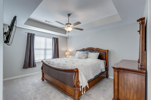 bedroom featuring light colored carpet, a raised ceiling, and ceiling fan