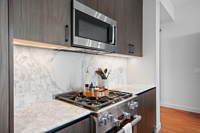 kitchen featuring tasteful backsplash, dark brown cabinetry, light hardwood / wood-style floors, and appliances with stainless steel finishes