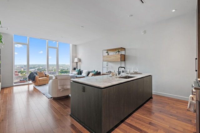 kitchen featuring expansive windows, sink, an island with sink, and dark hardwood / wood-style floors