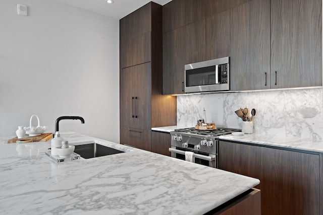 kitchen featuring backsplash, sink, light stone countertops, and stainless steel appliances