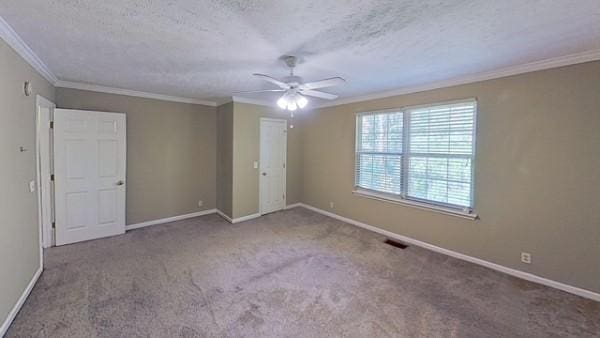 carpeted empty room featuring ornamental molding, ceiling fan, and a textured ceiling