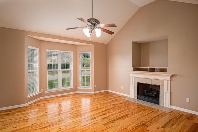 unfurnished living room with ceiling fan, light hardwood / wood-style floors, a tile fireplace, and vaulted ceiling