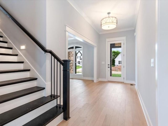 entrance foyer featuring crown molding and light hardwood / wood-style floors