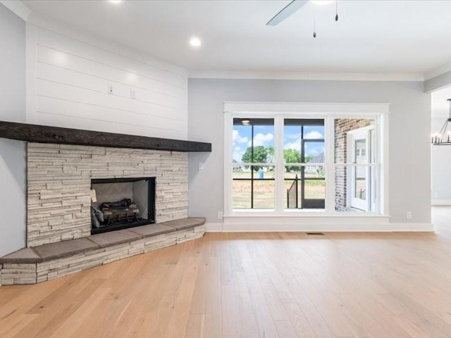 unfurnished living room with a fireplace, wood-type flooring, ceiling fan with notable chandelier, and ornamental molding