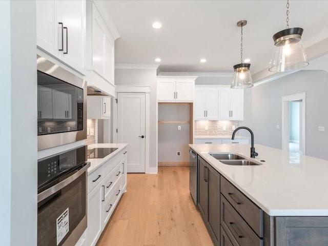 kitchen with white cabinets, pendant lighting, stainless steel appliances, and sink