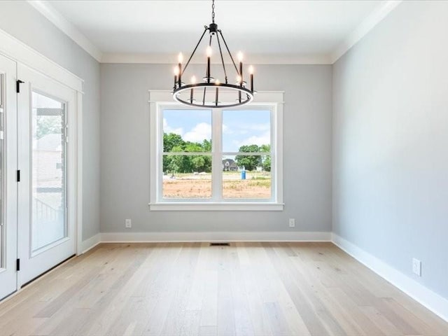 unfurnished dining area featuring crown molding, light hardwood / wood-style flooring, and a notable chandelier