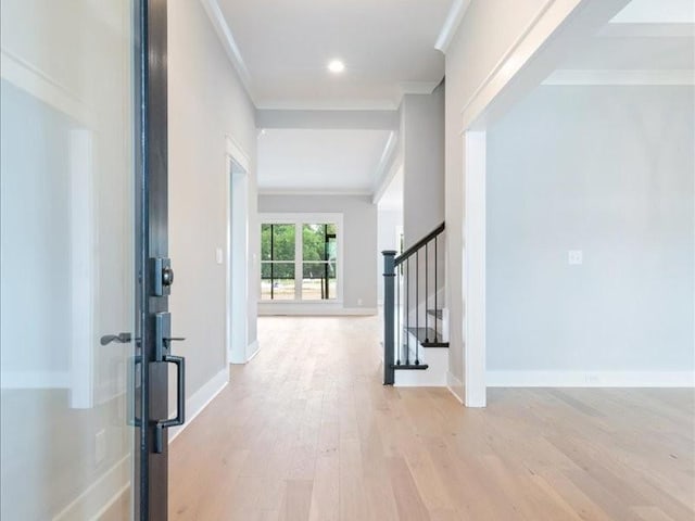 corridor with light hardwood / wood-style flooring and crown molding