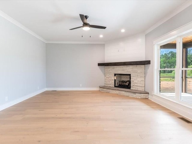 unfurnished living room featuring light wood-type flooring, a stone fireplace, ceiling fan, and ornamental molding