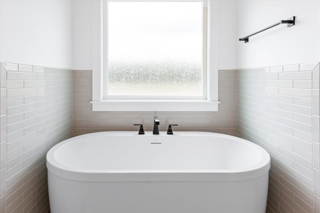 bathroom with a bath and tile walls