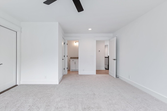 unfurnished bedroom with light carpet, ensuite bathroom, and ceiling fan