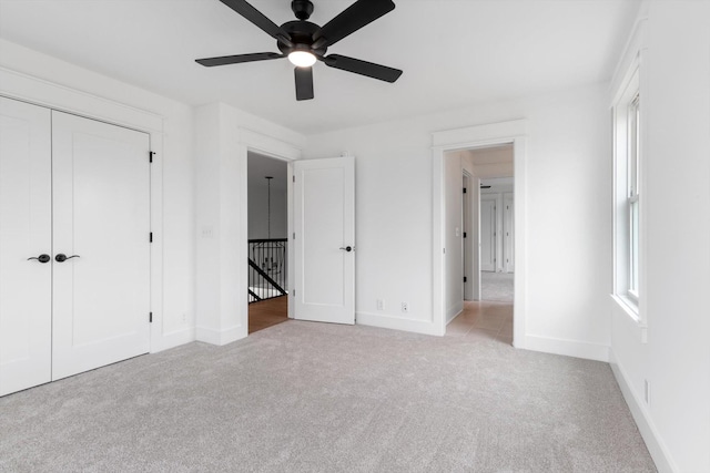 unfurnished bedroom with multiple windows, light colored carpet, a closet, and ceiling fan