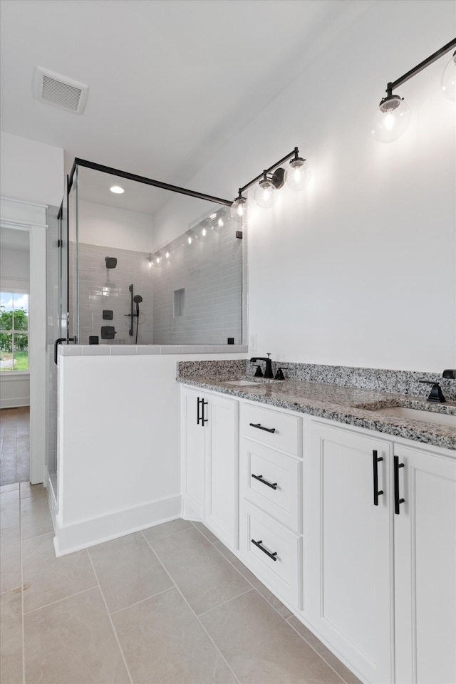 bathroom featuring a tile shower, vanity, and tile patterned floors