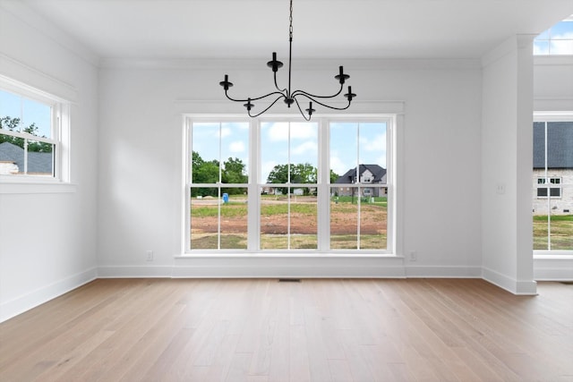 unfurnished dining area featuring crown molding, light hardwood / wood-style flooring, and a notable chandelier