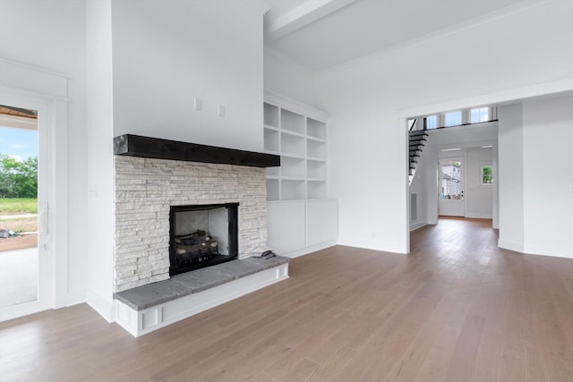 unfurnished living room featuring a fireplace, beamed ceiling, and wood-type flooring