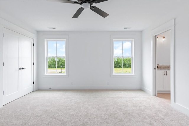 unfurnished bedroom featuring multiple windows, light carpet, a closet, and ceiling fan