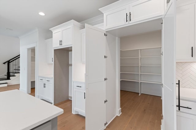 kitchen with white cabinetry, decorative backsplash, and light wood-type flooring