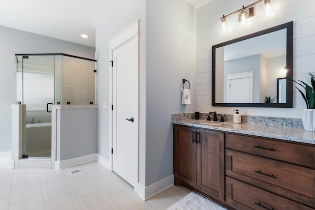 bathroom featuring tile patterned floors, vanity, and a shower with door