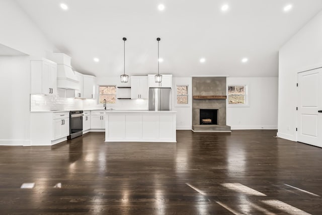 kitchen featuring a center island, white cabinets, sink, appliances with stainless steel finishes, and decorative light fixtures