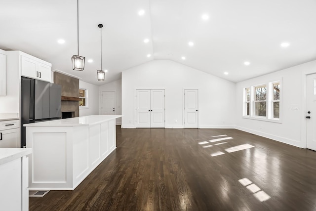 kitchen with decorative light fixtures, white cabinetry, dark hardwood / wood-style floors, stainless steel refrigerator, and lofted ceiling