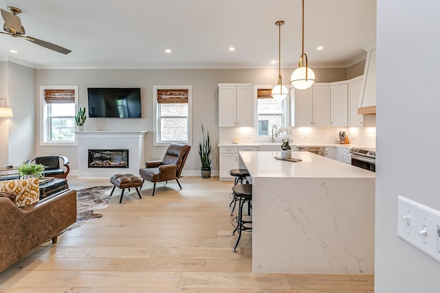 kitchen featuring stainless steel electric range, a center island, white cabinets, sink, and hanging light fixtures