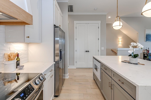 kitchen with decorative backsplash, appliances with stainless steel finishes, light stone countertops, premium range hood, and pendant lighting